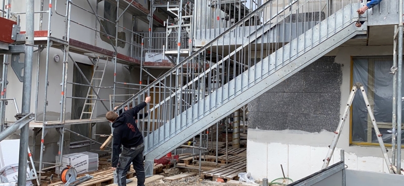 Zwei Bauarbeiter montieren eine gerade Stahltreppe
